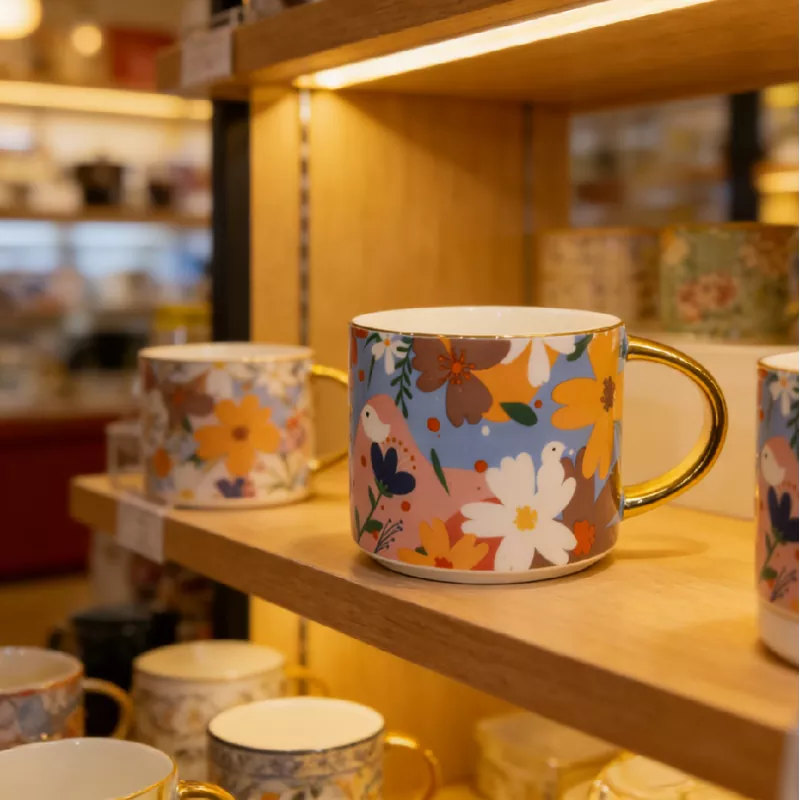 Lebhafte, florale Keramiktasse mit Goldbesatz Lebhafte, florale Keramiktasse mit Goldbesatz